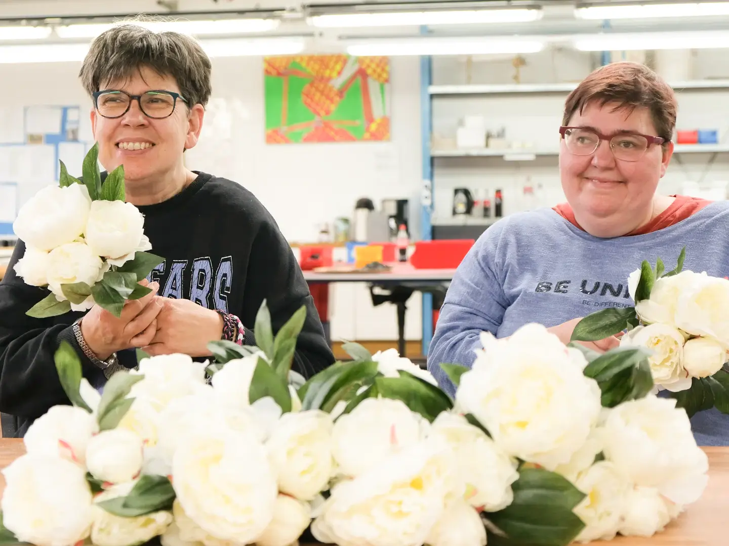 Frauen binden Pfingstrosen zu Blumensträußen