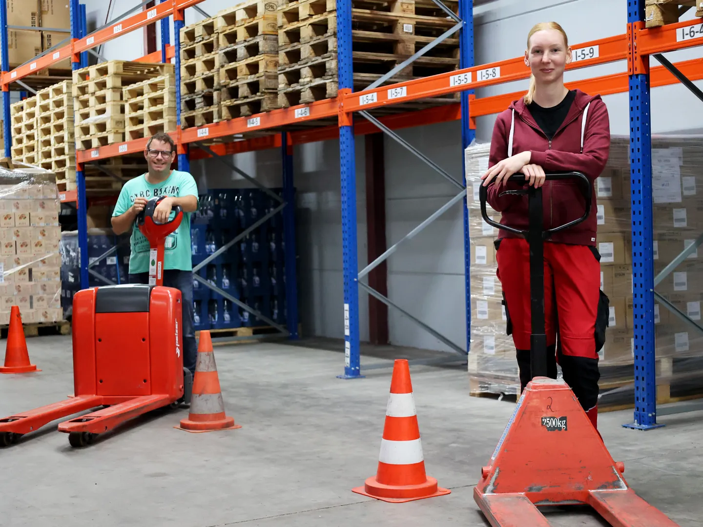 Mann und Frau mit Gabelhubwagen in der Lagerhalle