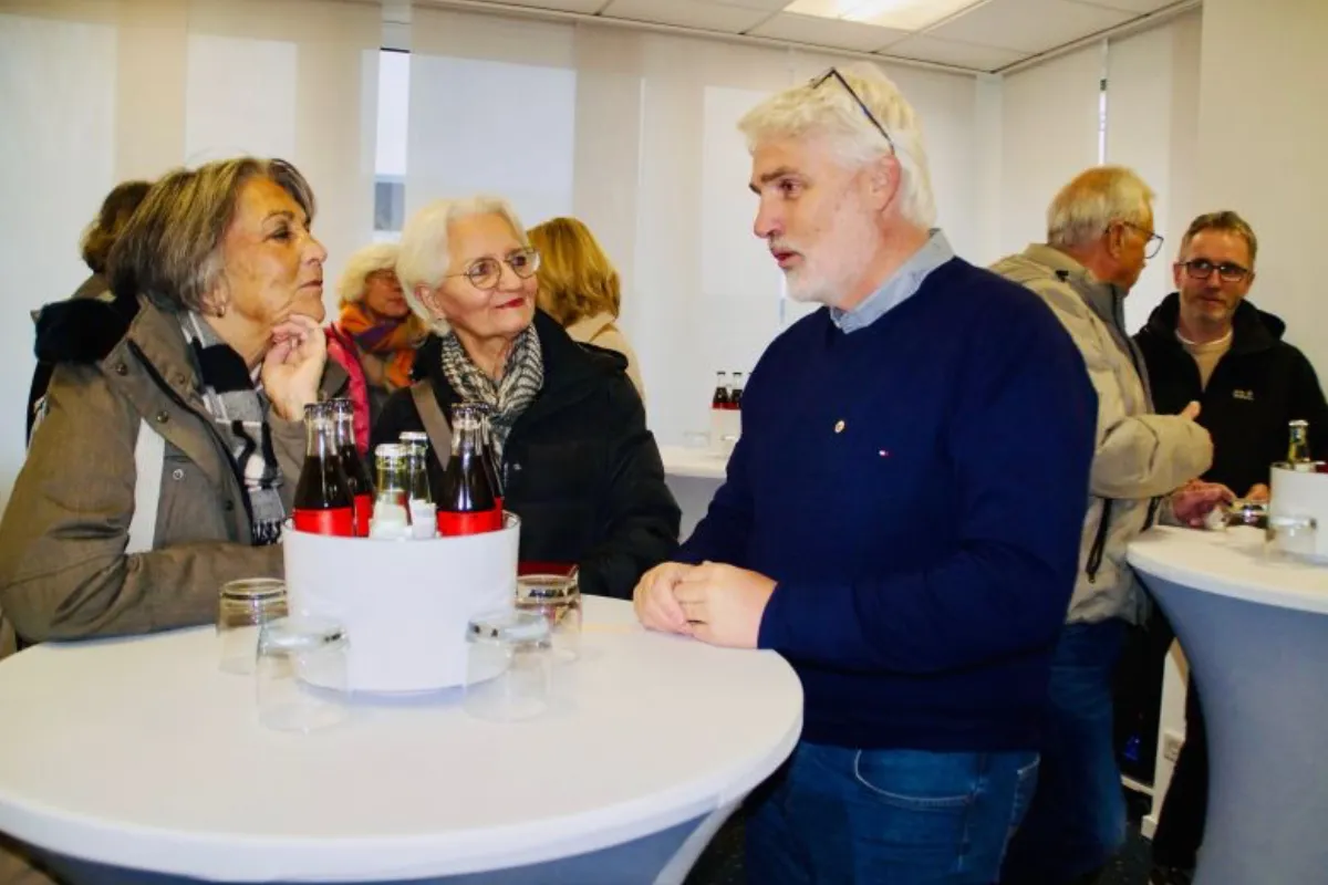 Eine Gruppe von Menschen steht um einen Stehtisch und führt ein Gespräch. Es handelt sich um einen Besuch des Lions Clubs Bergheim bei den REHA-Betrieben Erftland gGmbH.