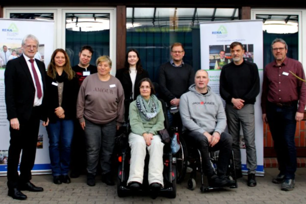 Dieter Freytag steht mit einer Gruppe von Besuchern und Werkstattbeschäftigten vor der Betriebsstätte Brühl der REHA-Betriebe