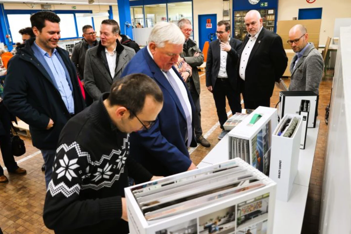 Karl-josef Laumann in unserer Musterproduktion. Er lässt sich von einem Werkstattbeschäftigten ein Musterbuch zeigen.