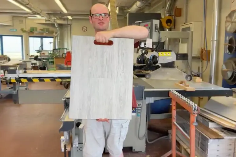 Ein Werkstattbeschäftigter zeigt eine seiner professionell gefertigten Mustertafeln.