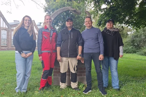 Ein Team der REHA Betriebe steht von der Anker-Statue der Firma Anker