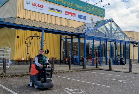 Christoph auf der Reinigungmaschine vor dem Gebäude des Werkzeugfachhandels Stabilo