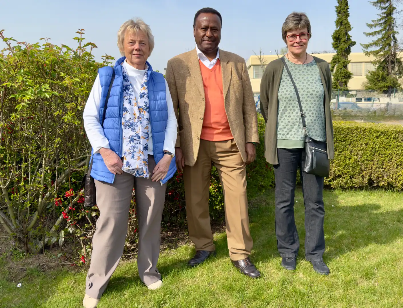 Der Elternbeirat REHE Betriebe Erftland gGmbH: Drei Personen stehen bei schönem Wetter auf einer Grünfläche der REHA-Betriebe Erftland.